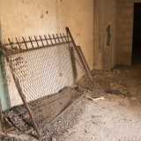 Appoggiato a un muro c'� un pezzo di ringhiera circondato dalla polvere...